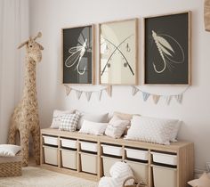 there are three pictures hanging on the wall in this child's room, and one has a giraffe