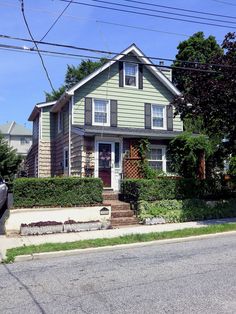 a green house with bushes on the front and side