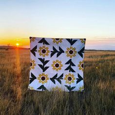 the sun is setting behind a quilt in a field