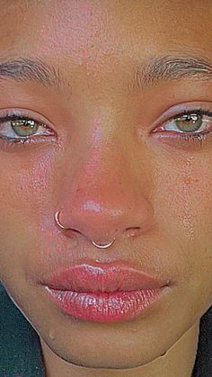 a close up of a woman's face with tears on her cheek and nose