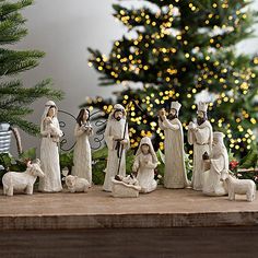 a group of figurines on a table in front of a christmas tree