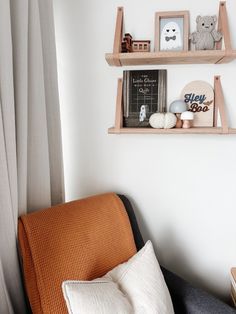 two wooden shelves on the wall above a couch with pillows and stuffed animals in it