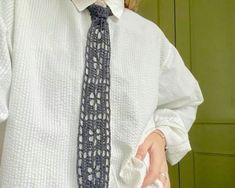 a woman wearing a white shirt with a blue tie on her left hand and a green wall in the background