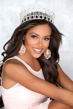 a beautiful young woman wearing a tiara and smiling at the camera with her arms crossed