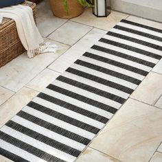 a black and white striped rug sitting on top of a floor next to a basket