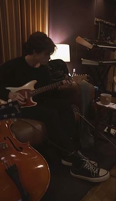 a man sitting in a chair playing an electric guitar