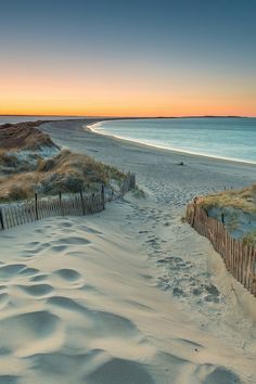 the beach is covered in sand as the sun sets