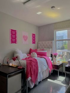 a bed room with a neatly made bed next to a large window and a desk