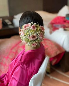 a woman with flowers in her hair sitting on a bed