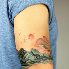 a man with a mountain landscape tattoo on his arm