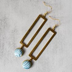 Catch some beach vibes with our Sandy Beaches Earrings! These blue and gold beauties feature a fun ocean print and a long rectangle charm. Perfect for adding a touch of seaside charm to any outfit. Due to the handmade nature of this product, no two earrings are exactly the same. Product Details 3.5" long x 0.75" wide Gold plated french hooks, nickel free Raw brass charm Gold plated pendant tray Glass cabochon Cotton fabric Care Instructions Keep earrings dry, remove when cleaning or near water. Clean with a soft cloth. Store in a dry, enclosed container. Rectangular Summer Earrings As Gift, Blue Rectangular Earrings, Blue Rectangular Earrings With Ear Wire, Bohemian Rectangular Jewelry For Summer, Gold Rectangular Jewelry For Summer, Rectangular Gold Summer Jewelry, Bohemian Rectangular Summer Jewelry, Rectangular Gold Jewelry For Summer, Handmade Fabric Earrings