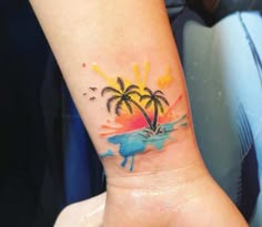 a small palm tree tattoo on the left inner arm and wrist with watercolors