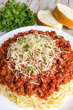 a plate of spaghetti with parmesan cheese and bread on the side for garnish