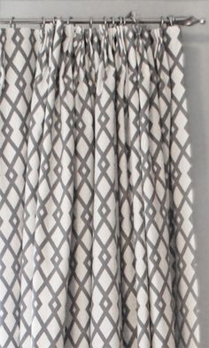 the curtains are hanging in front of a window with grey and white patterns on it