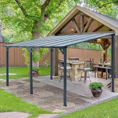 an outdoor covered patio with tables and chairs under a large shade structure in the backyard