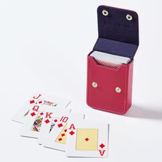 four playing cards in a red case next to an unopened deck of cards