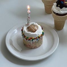 an ice cream cupcake with a candle on it and three cones in the background