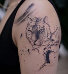 a woman's arm with a tiger tattoo on the left side of her shoulder