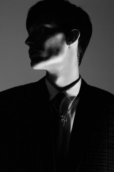 black and white photograph of a man in a suit with his face partially obscured by shadows