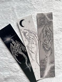 three bookmarks with designs on them sitting next to each other in front of a white background