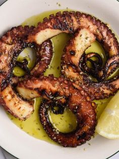 grilled octopus rings with olives and lemon on a white plate, ready to be eaten