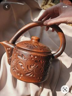 a person is holding a tea kettle on a bed