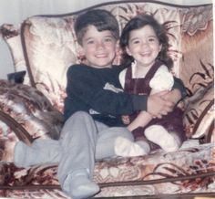 two children sitting on a couch smiling for the camera