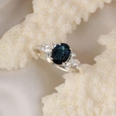 a blue diamond ring sitting on top of a white cloth