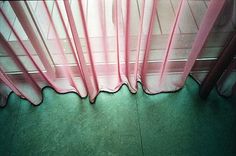 a pink curtain is hanging in front of a window