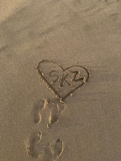 a heart drawn in the sand with footprints