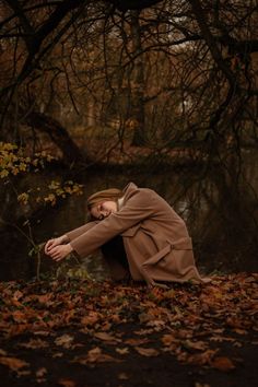 a woman kneeling on the ground next to a tree