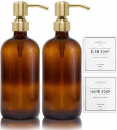 two brown glass soap dispensers with gold faucet handles and labels