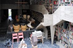 a room filled with lots of books and furniture next to a stair case full of books