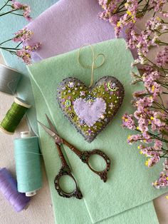 a pair of scissors sitting on top of a piece of cloth next to some flowers