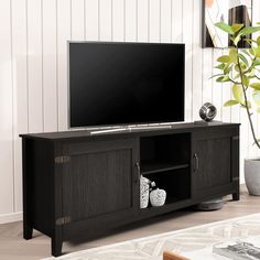 an entertainment center with a large flat screen tv on it's stand, in front of a white wall