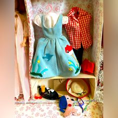 a doll's dress and hat are sitting on a shelf in a toy box