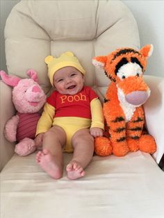 a baby sitting in a chair next to two stuffed animals and a winnie the pooh doll