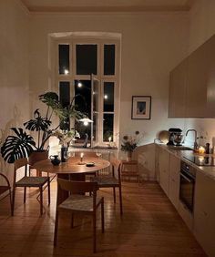 a dining room table and chairs in front of a window with potted plants on it