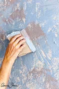 a person using a sponge to paint a wall with blue and white paint on it