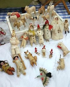 a table topped with lots of different types of stuffed animals and people on top of snow covered ground