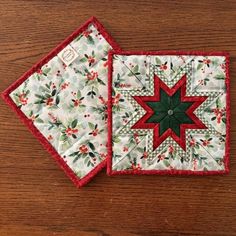 two quilted placemats sitting on top of a wooden table next to each other