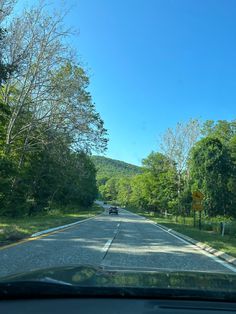 a car is driving down the road with trees on both sides