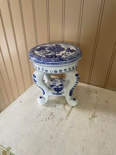 a blue and white vase sitting on top of a table next to a wooden wall