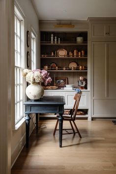 a dining room table with flowers in a vase on it