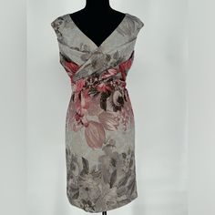 a dress on a mannequin is shown with flowers and leaves in the back