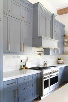 a kitchen with blue cabinets and white counter tops, gold pulls on the hoods