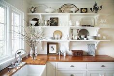 a kitchen with shelves filled with dishes and plates on top of the countertop next to a sink