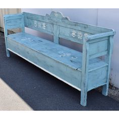 an old blue wooden bench sitting on the side of a road next to a building