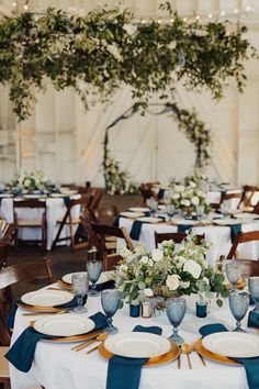 the tables are set with blue and white linens, silverware, and greenery