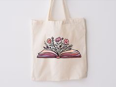 an open book with flowers on it is hanging from the wall next to a canvas bag